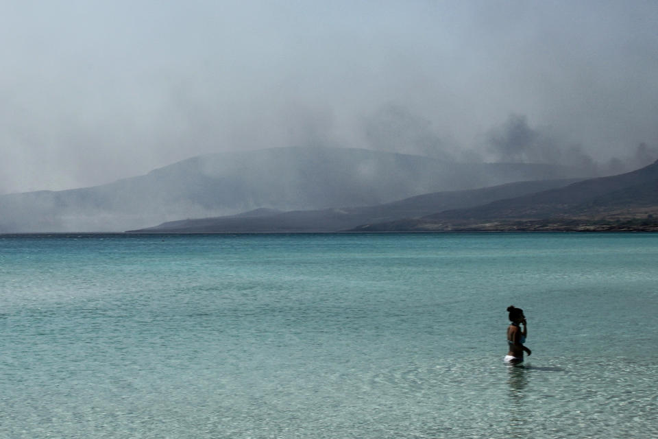 A cloud of smoke rises from a forest fire at Elafonisos island, south of Peloponnese peninsula, on Saturday, Aug. 10, 2019. A wildfire which broke out on Elafonisos island in southern Greece on Saturday has prompted the evacuation of a hotel and camping as a precautionary measure, with no injuries reported, according to Greek national news agency AMNA. (AP Photo/Nikolia Apostolou)