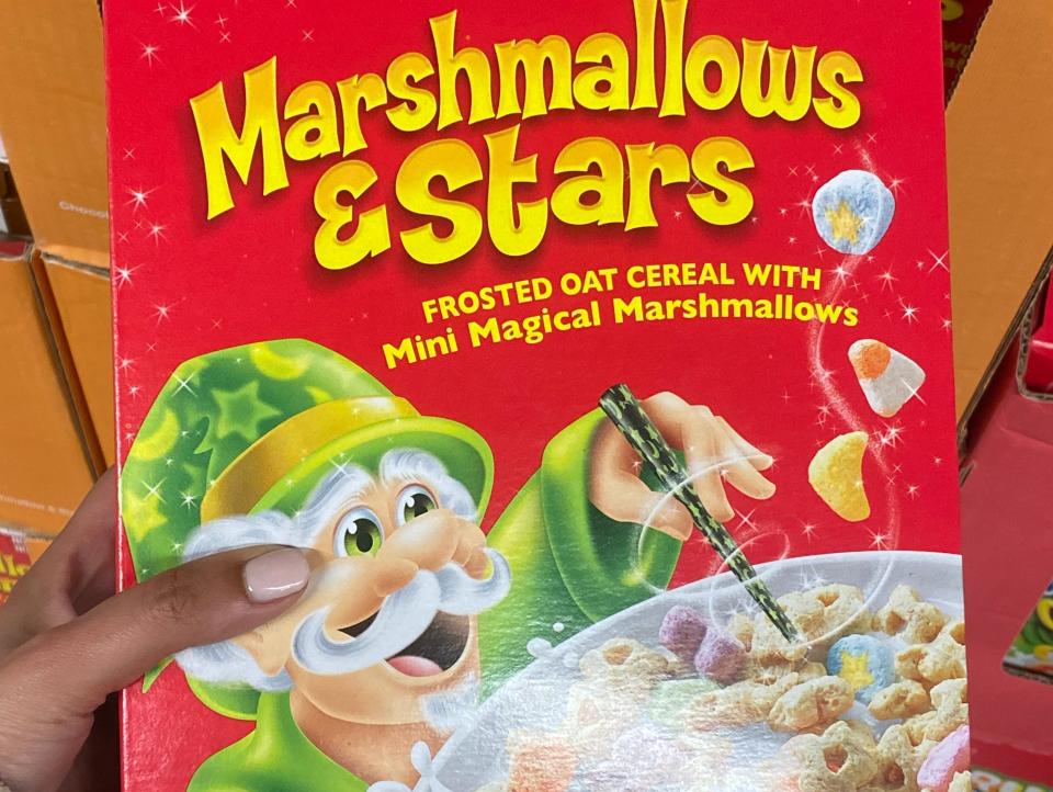 Hand holding red box of marshmallows and stars cereal at Aldi