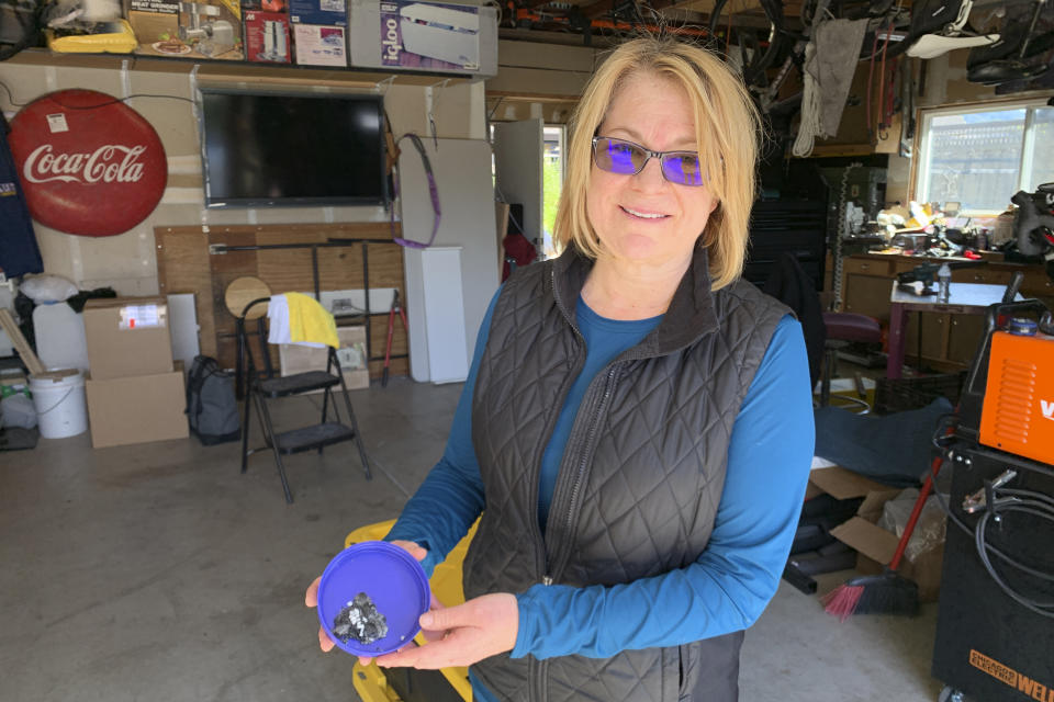 Brenda Catelani stands in her garage and shows ember she found in her backyard in Windsor, Calif, Thursday, Oct. 31, 2019. She and her husband were evacuated for four nights as firefighters battled the Kincade Fire, which reached the edge of their neighborhood. The fire was the largest to burn over a three-week siege of gusty winds that fanned fast-moving wildfires across California and led utility companies to cut power to millions to prevent breezes from blowing branches into electric lines and igniting an inferno. (AP Photo/Terry Chea)