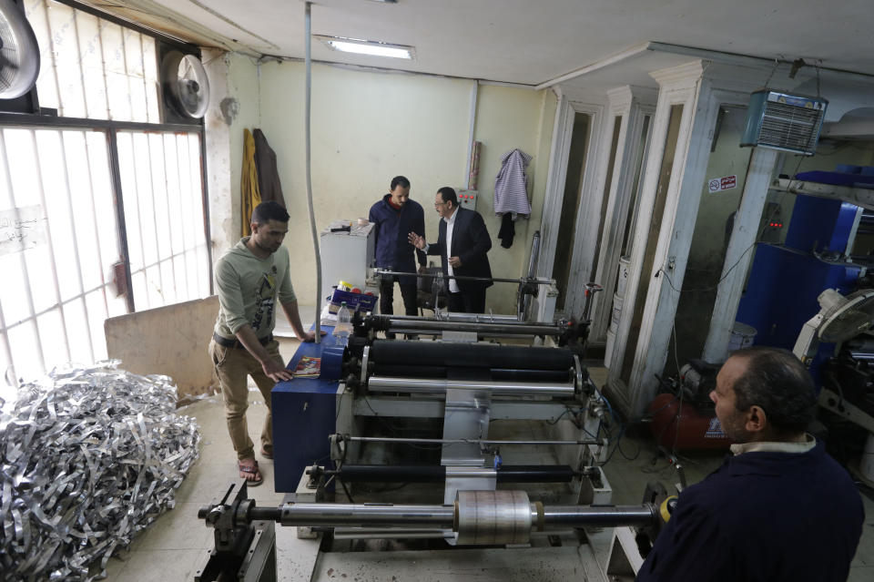 In this Monday, March 3, 2014 photo, Adel Abd ElSadk, owner of the pharmaceutical packaging company Trustpack, second right, talks with an employee manning one of the machines at his factory which has been financed in part by loans from the Social Development Fund, located just outside Cairo, Egypt. The program, called “The Project” in Arabic, highlights entrepreneurship and small business acumen - something experts say is more crucial than ever as Egypt tries to claw its way out of tough economic times. (AP Photo/Amr Nabil)