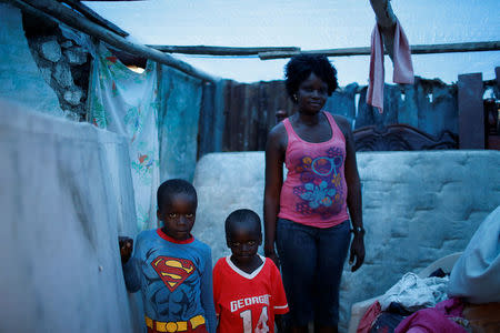 Marie Ange St Juste (R), 29, poses for a photograph with her sons, Kensley, 7 (L), and Peterley, 5, in their destroyed house after Hurricane Matthew hit Jeremie, Haiti, October 17, 2016. "My house was totally destroyed during the storm," said St Juste. "I lost everything, but I was lucky that none of my children died. Now my situation is very bad, we need help." REUTERS/Carlos Garcia
