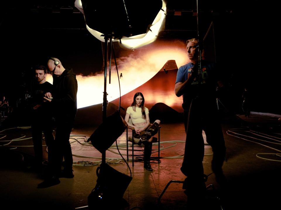 polachek sits in a chair on the set of a music video