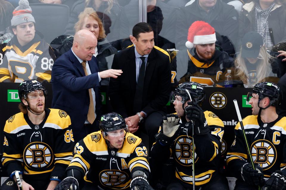 Boston Bruins coach Jim Montgomery, top left, talks to left wing Jake DeBrusk (74) on the bench during a recent game.