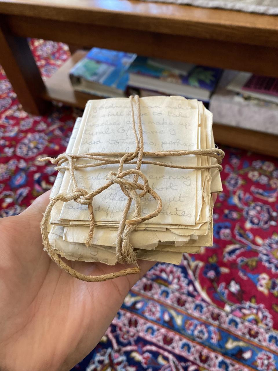 A person's hand holding a bundle of tied old letters