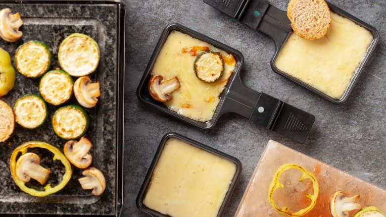 mini raclette skillets with vegetables on countertop
