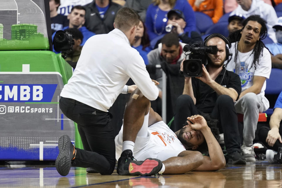 Miami forward Norchad Omier is tended to after being injured during the first half of an NCAA college basketball game against Duke at the Atlantic Coast Conference Tournament in Greensboro, N.C., Friday, March 10, 2023. (AP Photo/Chuck Burton)