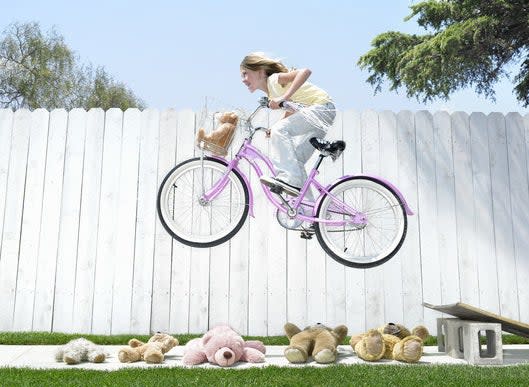 A kid jumping over teddy bears on a bike