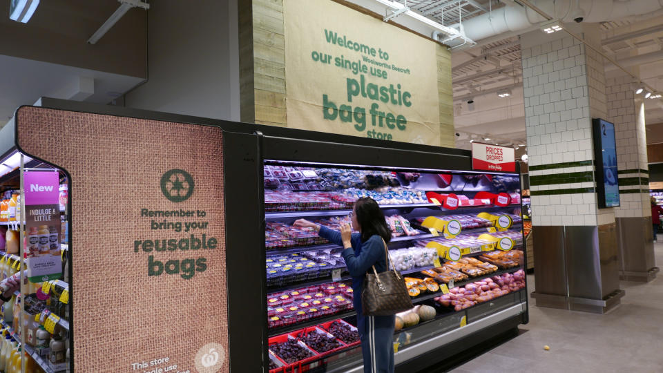 Shopper at Woolworths interior next to sign that says &#39;we are a plastic bag free store&#39;. Source: Jill Gralow/Reuters