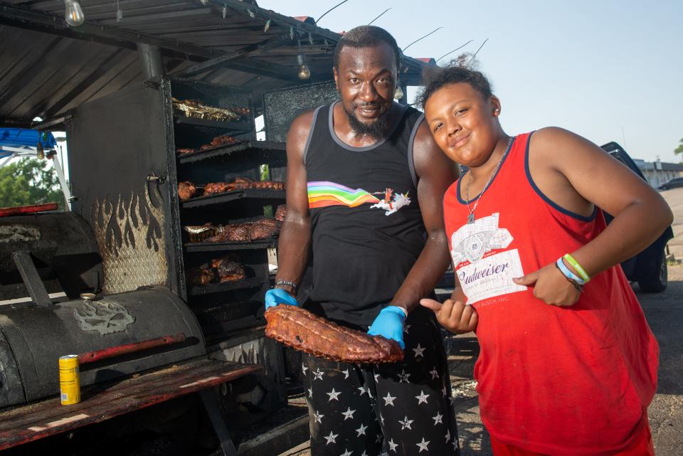 Smokey Dunks owner Duncan Lee holds up a slab of smoked ribs as he poses with his son Malachi Lee, 12, in the parking lot in front of the Owls Nest, 3411 S.W. Topeka Blvd. Customers can place orders through apps like Grubhub or stop by to order directly.