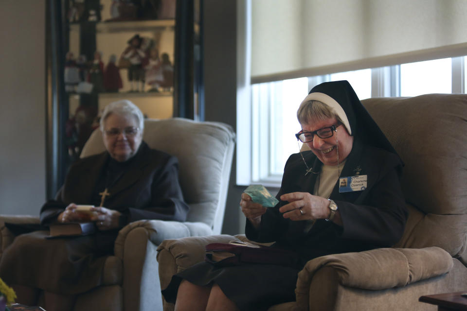 Sister Mary Charlene Ozanick, of the Felician Sisters of North America, right, laughs at a motivational quote written on a bar of soap given to her by a fellow nun at St. Anne Home in Greensburg, Pa., on Thursday, March 25, 2021. (AP Photo/Jessie Wardarski)