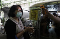 A woman's temperature is measured before riding a passenger jeepney to help curb the spread of COVID19 as drivers at the Tandang Sora terminal were recently allowed back on the road after months of not being able to work on Sunday, Aug. 2, 2020 in Quezon city, Philippines. Coronavirus infections in the Philippines continues to surge Sunday as medical groups declared the country was waging a losing battle against the contagion and asked the president to reimpose a lockdown in the capital. (AP Photo/Aaron Favila)