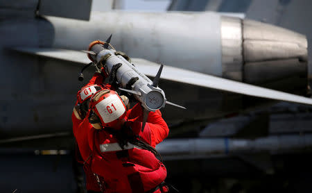 U.S. Navy personnel carry a missile to arm an F18 fighter jet at the deck of USS Carl Vinson during a FONOPS (Freedom of Navigation Operation Patrol) in South China Sea, March 3, 2017. REUTERS/Erik De Castro