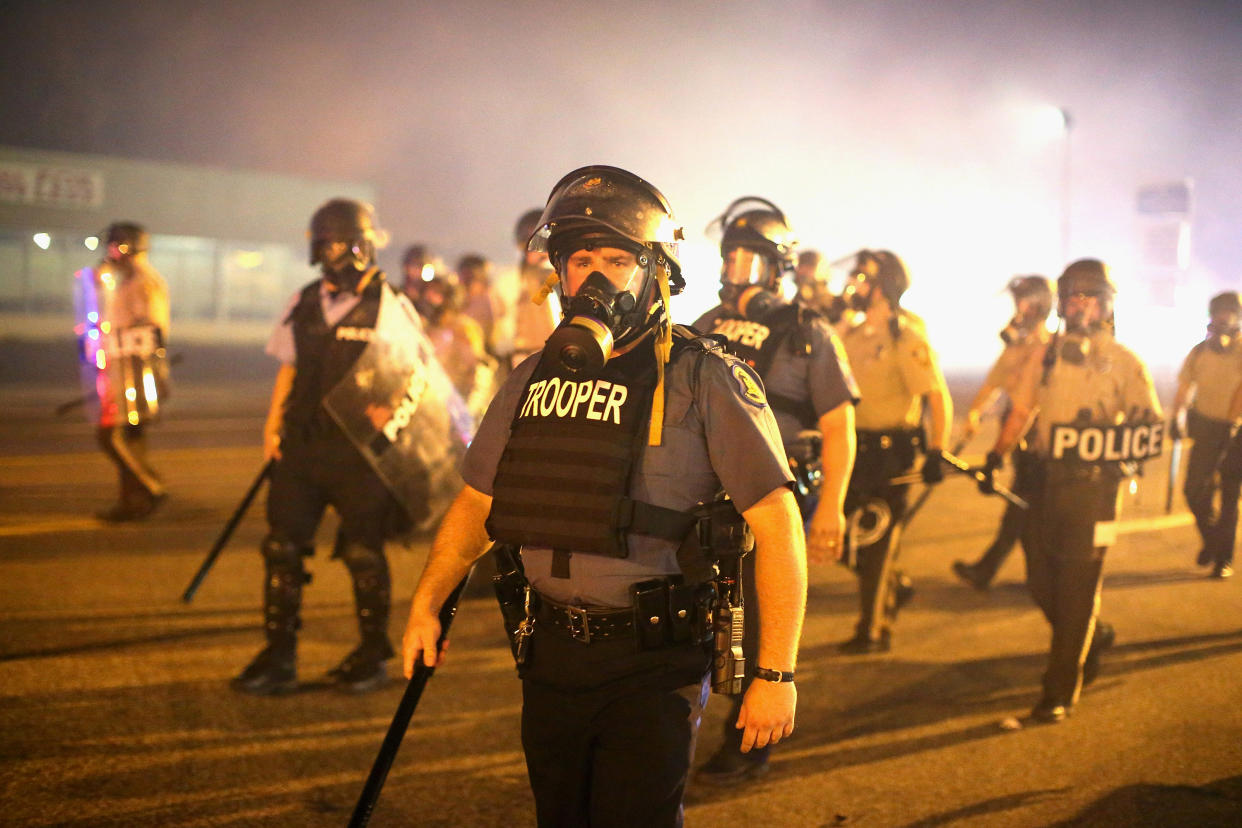 Police advance through a cloud of tear gas toward demonstrators protesting the killing of teenager Michael Brown on August 17, 2014 in Ferguson, Missouri. (Photo by Scott Olson/Getty Images)