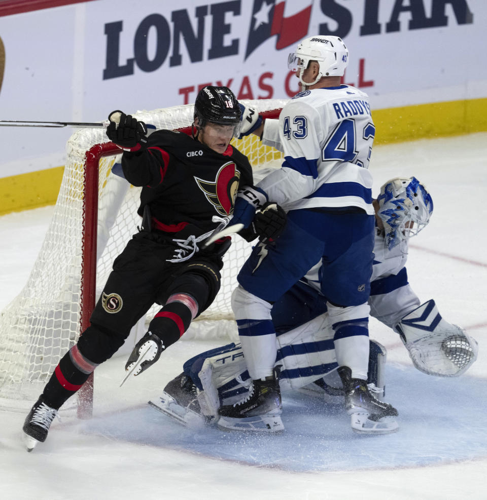 Tampa Bay Lightning goaltender Matt Tomkins makes a save as defenseman Darren Raddysh battles with Ottawa Senators left wing Tim Stutzle (18) in front of the net during the first period of an NHL hockey game, in Ottawa, Ontario, Sunday, Oct. 15, 2023. (Adrian Wyld/The Canadian Press via AP)