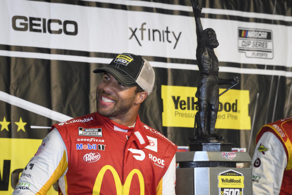 Bubba Wallace celebrates next to the trophy after winning a NASCAR Cup series auto race Monday, Oct. 4, 2021, in Talladega, Ala. The race was stopped mid-race due to rain. (AP Photo/John Amis)