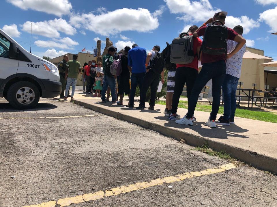 Migrants line up outside the Val Verde Border Humanitarian Coalition migrant shelter in Del Rio, Texas, after being released by U.S. Border Patrol. Many of the migrants will later take state-funded bus rides to Washington, New York or Chicago.