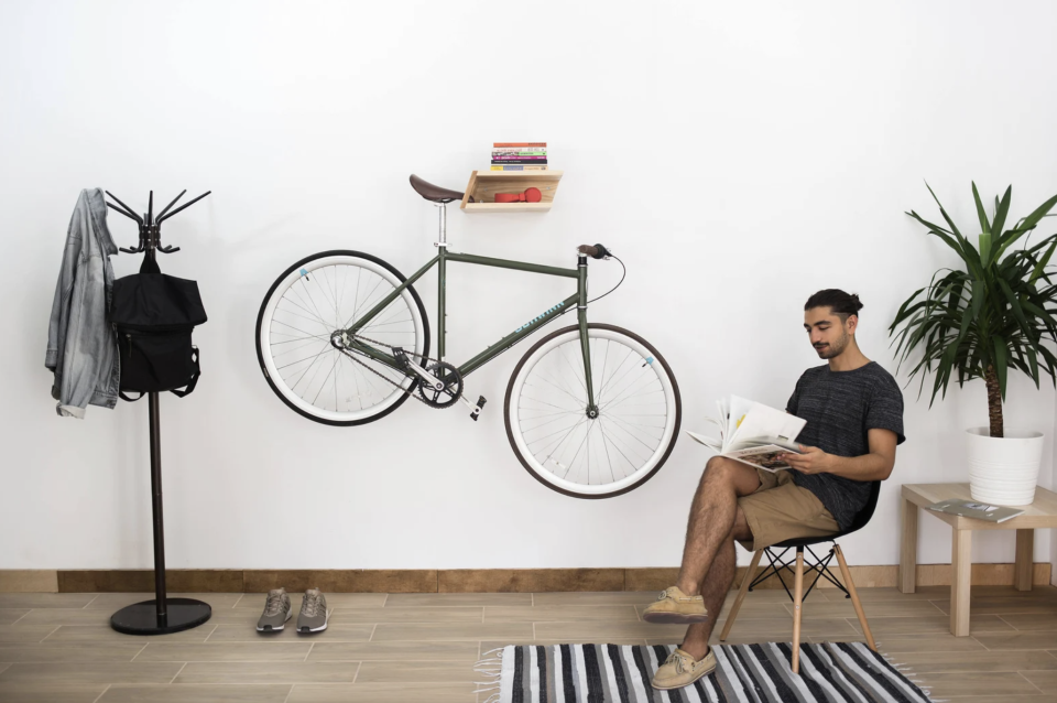 man sitting on chair next to bike on wall in Wooden Bike and Boar Rack (Photo via Etsy)