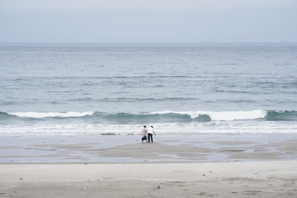 People walk along the shoreline of the Usuiso beach in Iwaki, northeastern Japan, Thursday, July 6, 2023. (AP Photo/Hiro Komae)