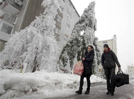 Enej Progar (R) and Armina Gasi leave their apartment after four days without electricity and heating, in Postojna February 5, 2014. REUTERS/Srdjan Zivulovic