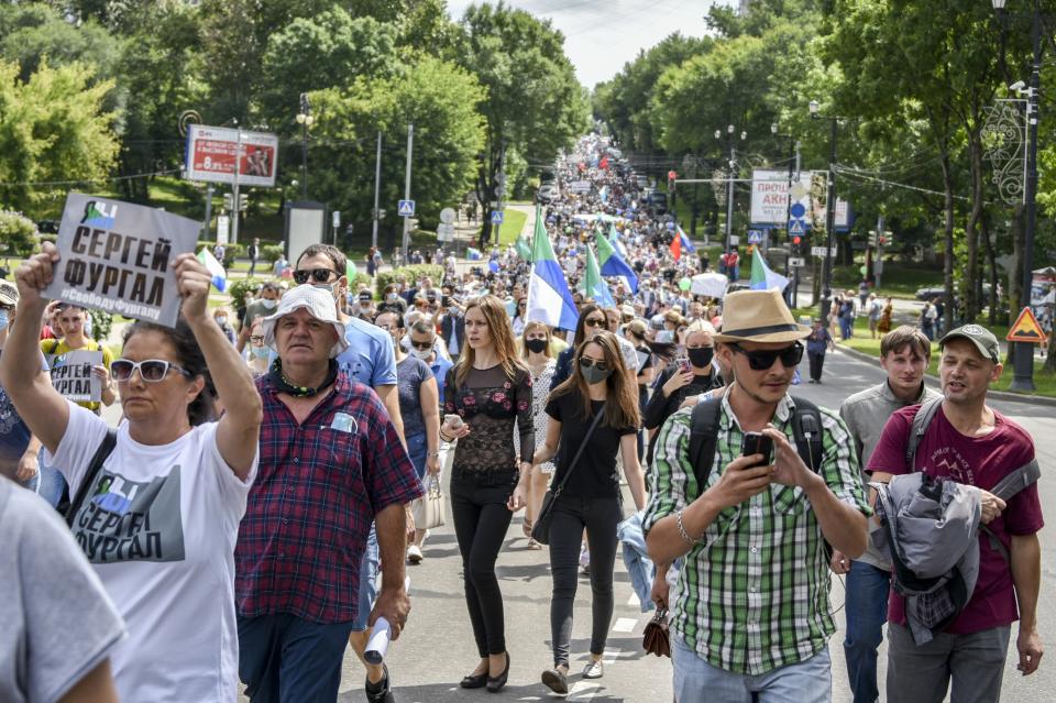 People hold posters that read: "I am, We are Sergei Furgal, Sergei Furgal our Governor", during an unsanctioned protest in support of Sergei Furgal, the governor of the Khabarovsk region, in Khabarovsk, 6100 kilometers (3800 miles) east of Moscow, Russia, Saturday, Aug. 8, 2020. Thousands of demonstrators have again gathered in the major Russian Far East city of Khabarovsk to denounce the arrest of the region's governor a month ago. Sergei Furgal was arrested on suspicion of involvement in murders and taken to jail in Moscow. The estimated 3,000 demonstrators in Khabarovsk protested the charges and want him returned to the city for trial. (AP Photo/Igor Volkov)