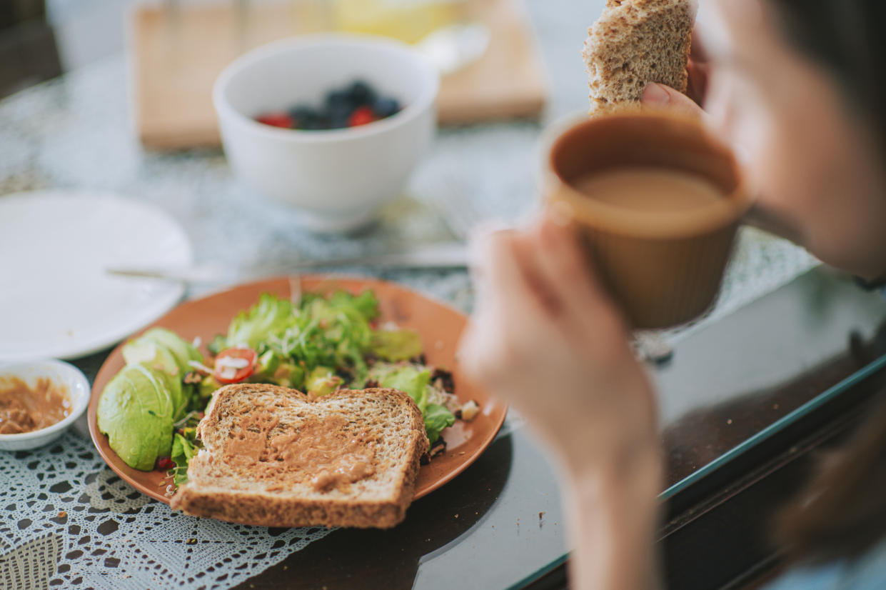 Asian chinese beautiful woman enjoying her breakfast at home drinking coffee eating salad and toasted bread in the morning