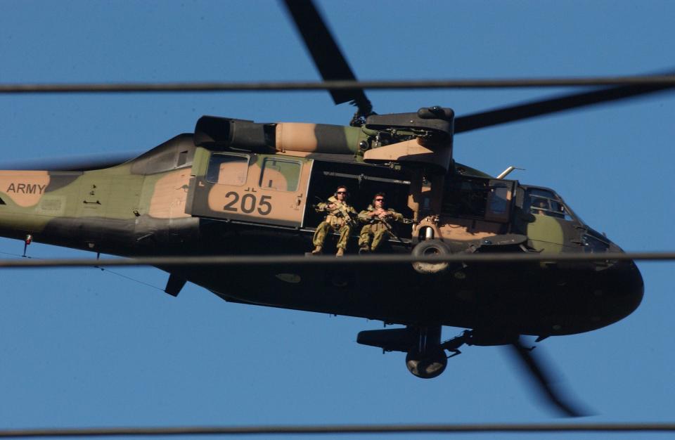 An Australian Special Air Service Regiment sniper team armed with SR-25 rifles flies overwatch in an Australian Army S-70A-9 Black Hawk for Australian infantry during street battles in downtown Dili, East Timor, during the military mutiny there in May 2006. <em>John Hunter Farrell</em><br>