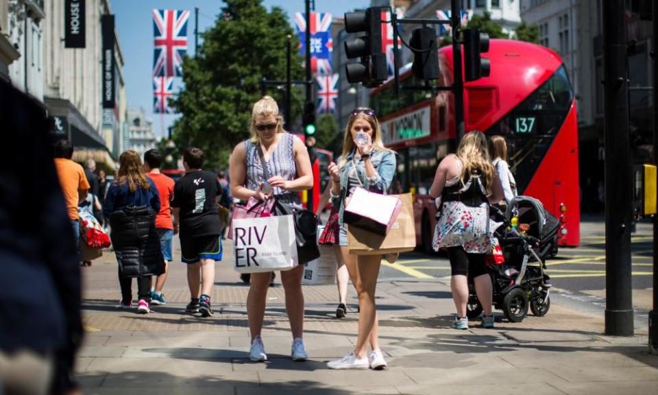 Two women shoppers armed with bags of shopping on Oxford Street, London