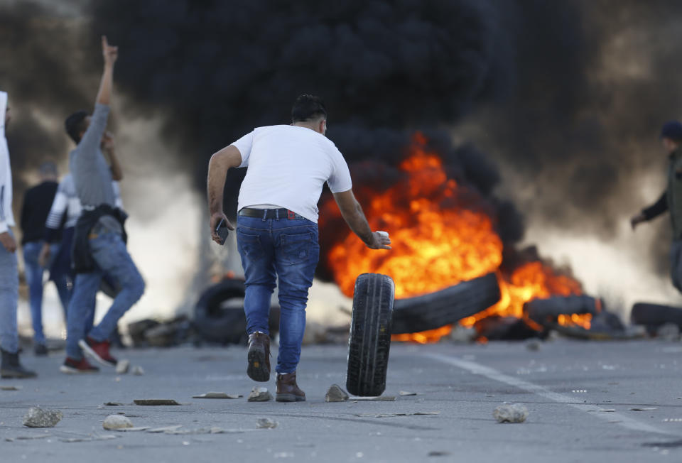 Palestinian protesters set tires on fire during clashes with Israeli troops at the Hawara checkpoint, south of the West Bank city of Nablus, Friday, Dec. 14, 2018. (AP Photo/Majdi Mohammed)