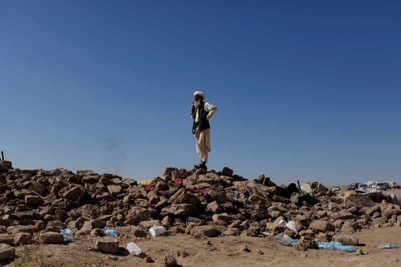 An Afghan man stands on the debris of damaged houses after the recent earthquake, in the district of Zinda Jan, in Herat