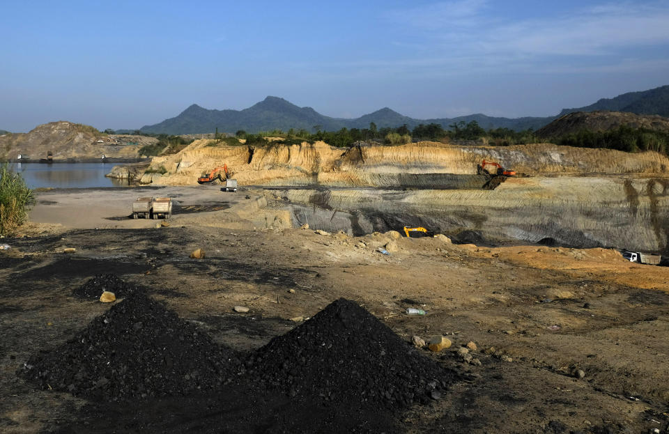 Tiny mounds of coal collected manually by villagers lie in front of machinery working at an open-pit coal mine in Tiru, near Oting, in the northeastern Indian state of Nagaland, Wednesday, Dec. 15, 2021. Six coal miners from this region were killed by Indian army soldiers on Dec. 4, and seven more from a search party were killed the same night. Collecting coal manually is back-breaking work with villagers sifting through waste soil dumped by heavy machinery digging in coal sites. (AP Photo/Yirmiyan Arthur)