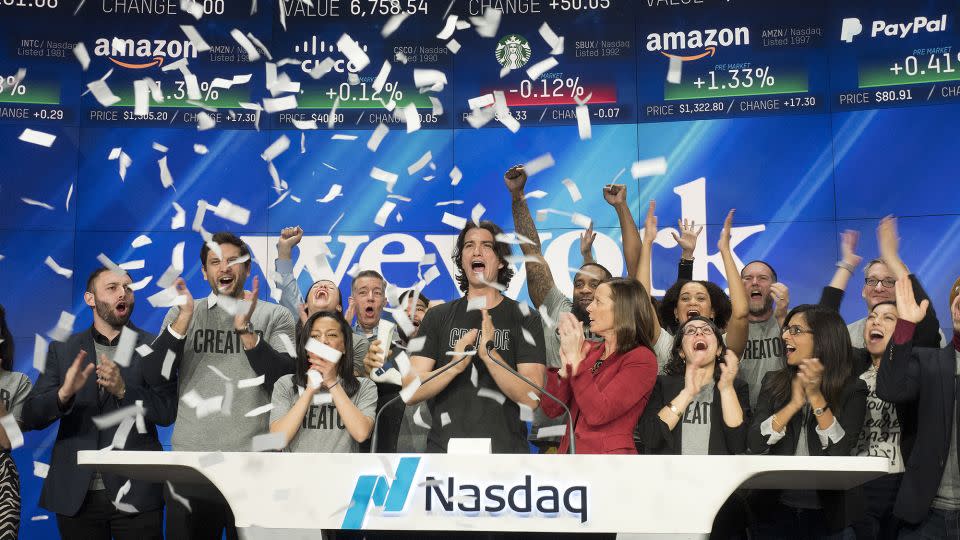 Adam Neumann, center, co-founder and CEO of WeWork, attends the opening bell ceremony at Nasdaq, Tuesday, Jan. 16, 2018, in New York. - Mark Lennihan/AP