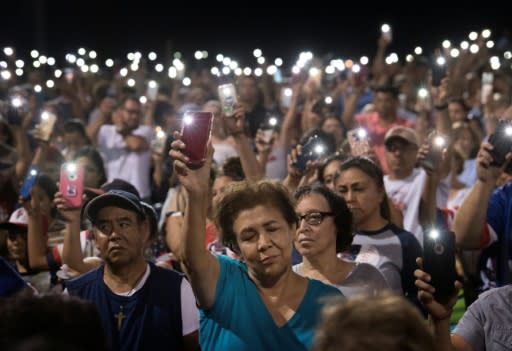 People hold up their phones during a prayer and candlelight vigil after a shooting left 22 people dead in El Paso, Texas