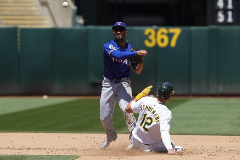 Texas Rangers second baseman Marcus Semien, left, turns a double play after forcing out Oakland Athletics' Max Schuemann at second during the fourth inning in the first baseball game of a doubleheader Wednesday, May 8, 2024, in Oakland, Calif. Esteury Ruiz was out at first on the play. (AP Photo/Godofredo A. Vásquez)