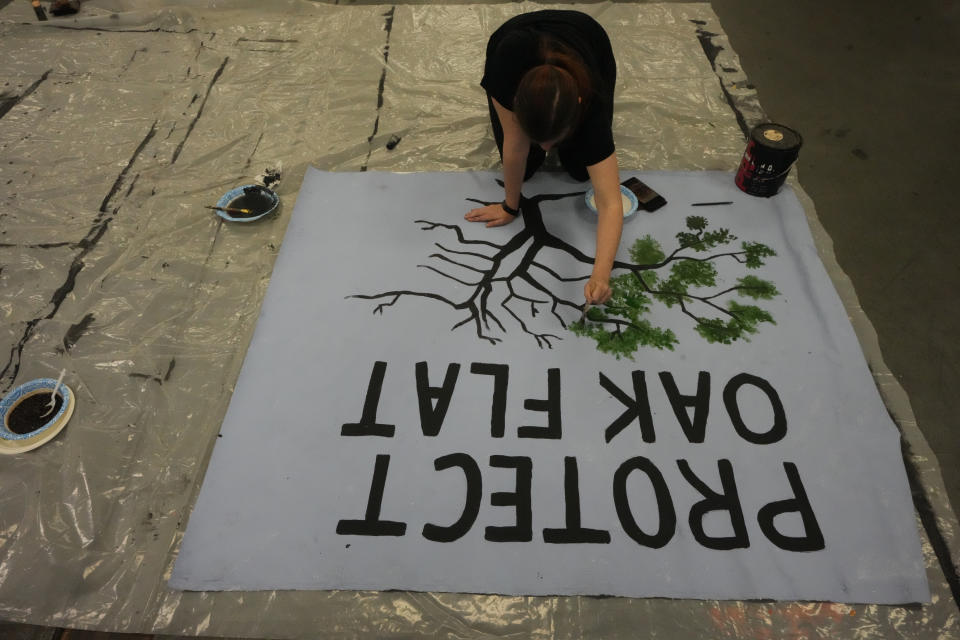 A member of the Apache Stronghold group who traveled from Arizona paints a protest banner at Self Help Graphics & Art in the Los Angeles neighborhood of Boyle Heights on Monday, March 20, 2023. The Apache group battling a foreign mining firm that wants to build one of the largest copper mines in the United States on what tribal members say is sacred land will get a new chance to make its point Tuesday when a full federal appeals court panel takes another look at the case. (AP Photo/Damian Dovarganes)