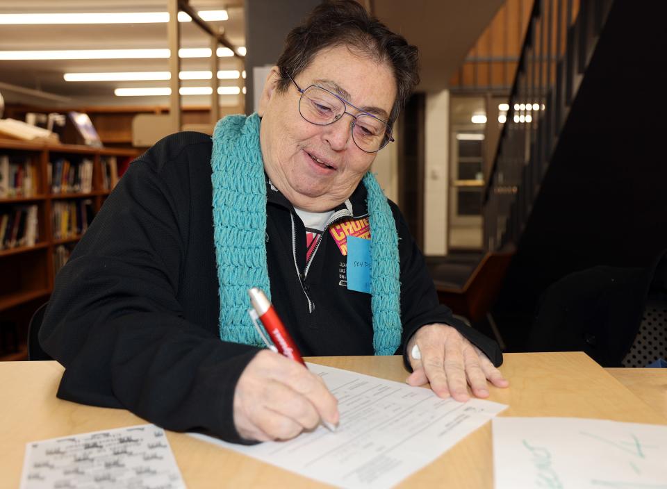 Valerie Madison completes paperwork as Democrats brave sub-zero weather to gather in person on Iowa Caucus night in Polk County on Monday at the East High School library in Des Moines.