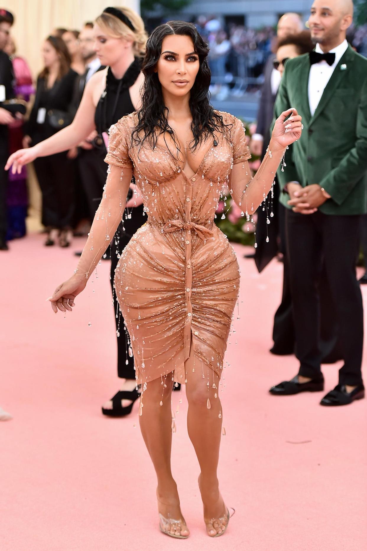 Kim Kardashian on the Met Gala red carpet wearing a formfitting sheer dress with crystal raindrop embellishments.