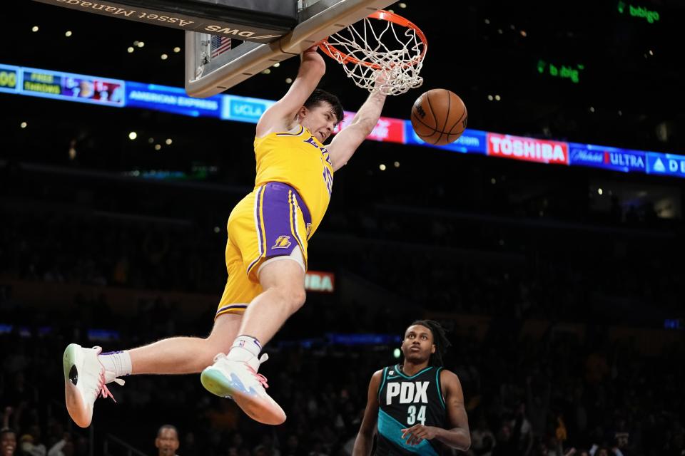 Los Angeles Lakers guard Austin Reaves, left, dunks as Portland Trail Blazers forward Jabari Walker defends during the first half of an NBA basketball game Wednesday, Nov. 30, 2022, in Los Angeles. (AP Photo/Mark J. Terrill)