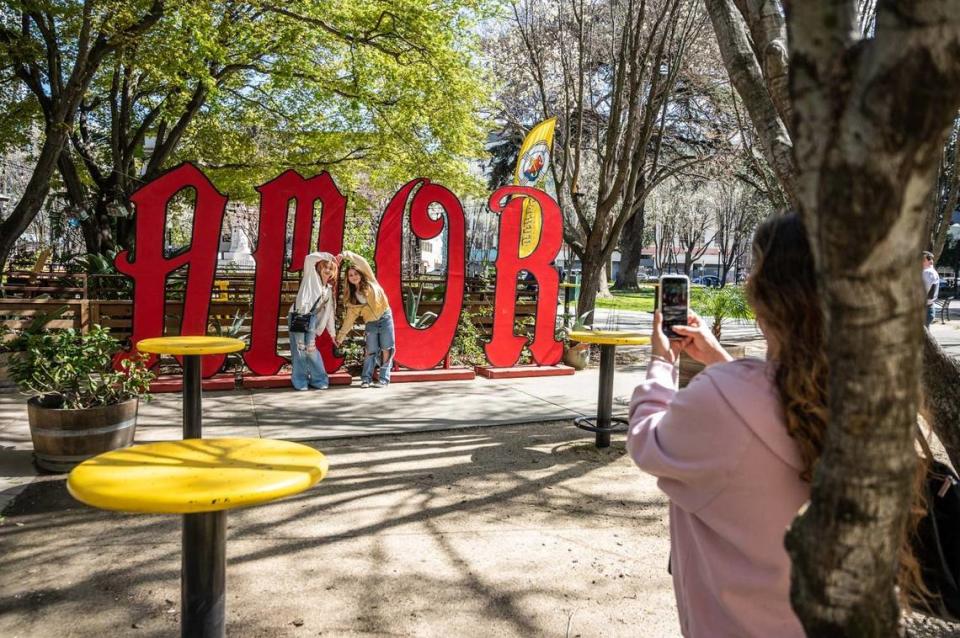 Skyla Pichardo and her friend Echidna Coleman, both 14, pose for a photo in front of an “amor” sign at La Cosecha restaurant at Cesar Chavez Plaza earlier this month.