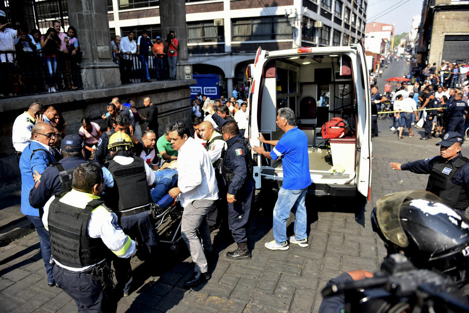 Police and paramedics attend a person who was wounded by a shooter outside City Hall in Cuernavaca, Mexico, Wednesday, May 8, 2019. A man opened fire at the entrance of City Hall where journalists were interviewing government officials, killing two people, including a union member who was apparently with street vendors who were protesting nearby, and injuring two others, including a TV cameraman, according to officials. (AP Photo/Tony Rivera)