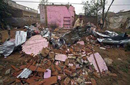 An Indian villager clears the debris from his house, which locals said was damaged by firing from the Pakistan side of the border, at Bainglad village in Samba sector, south of Jammu January 6, 2015. REUTERS/Mukesh Gupta