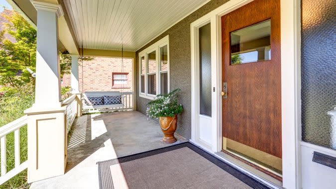 Front covered porch with hanging swing and flower pot.