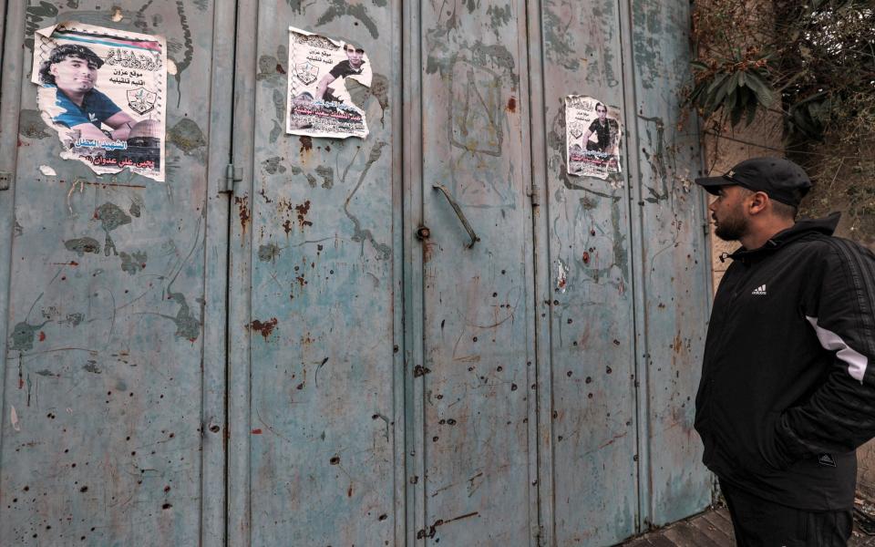 A man inspects bullet holes riddling the metal shutters outside a closed shop where Palestinians were reportedly shot in a confrontation during an Israeli military operation in the town of Azzun, east of Qalqilya in the occupied West Bank