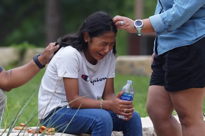 A girl cries comforted by two adults.