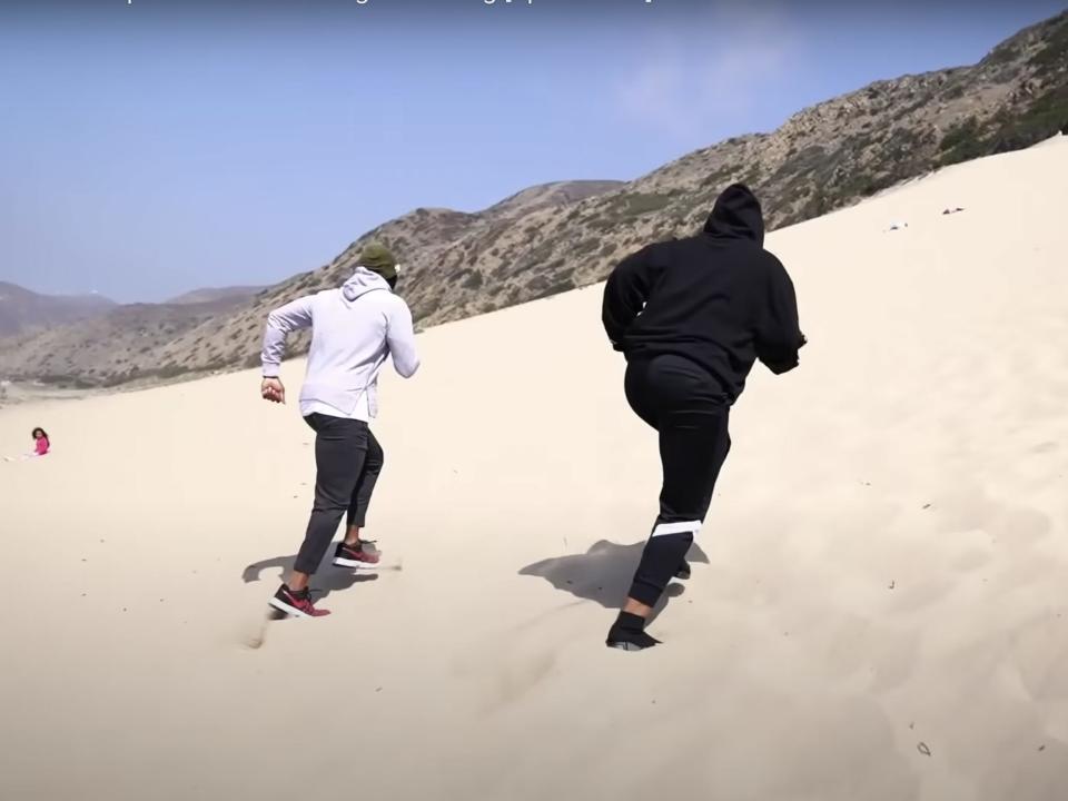 Megan Thee Stallion and her trainer running up a sand dune.