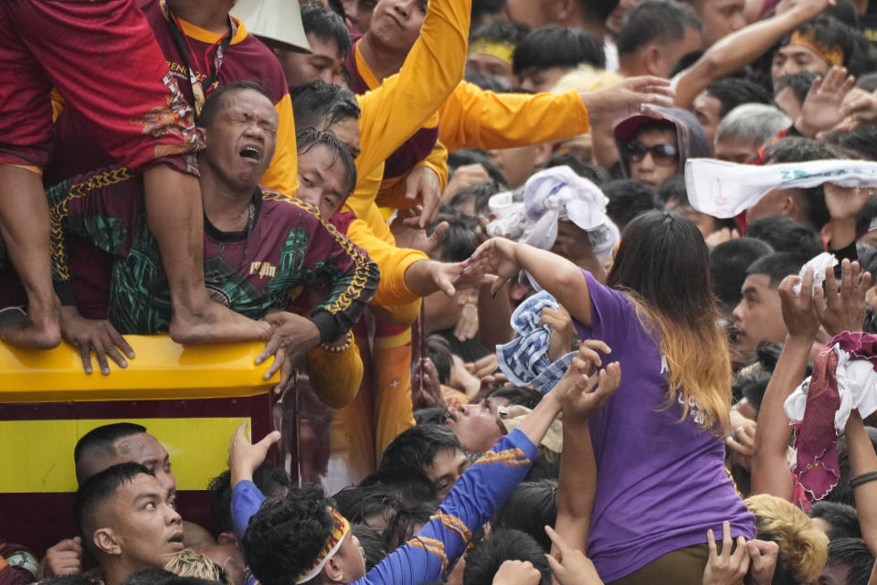 A devotee reacts as he tries to block other devotees from climbing the cart carrying the Black Nazarene during it's annual procession which was resumed after a three-year suspension due to the coronavirus pandemic on Tuesday, Jan. 9, 2024 in Manila, Philippines. A mammoth crowd of mostly barefoot Catholic devotees joined a chaotic procession through downtown Manila Tuesday to venerate a centuries-old black statue of Jesus Christ with many praying for peace in the Middle East where Filipino relatives work. (AP Photo/Aaron Favila)