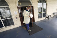 Dr. Robin Armstrong holds open the door to The Resort at Texas City nursing home, where he is the medical director, Tuesday, April 7, 2020, in Texas City, Texas. Armstrong is treating nearly 30 residents of the nursing home with the anti-malaria drug hydroxychloroquine, which is unproven against COVID-19 even as President Donald Trump heavily promotes it as a possible treatment. Armstrong said Trump's championing of the drug is giving doctors more access to try it on coronavirus patients. More than 80 residents and workers have tested positive for coronavirus at the nursing home. (AP Photo/David J. Phillip)