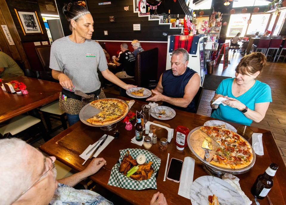 Server Catina Rogers, left, delivers a pizza to Dave Bowlby, center and his wife Charlotte, right, at Silver Springs Pizza Monday afternoon, January 30, 2023. Co-owner Jace Tyler attributes a great pizza to the ingredients he uses like Caputo flour from Italy to make his dough and the sauce is made from scratch along with quality ingredients. The restaurant is open Thursday from 11 a.m. to 9 p.m., Friday and Saturday 11 a.m. to 10 p.m., Sunday 11 a.m. to 8:30 p.m. and Monday from 4 p.m. to 9 p.m. [Doug Engle/Ocala Star Banner]2023