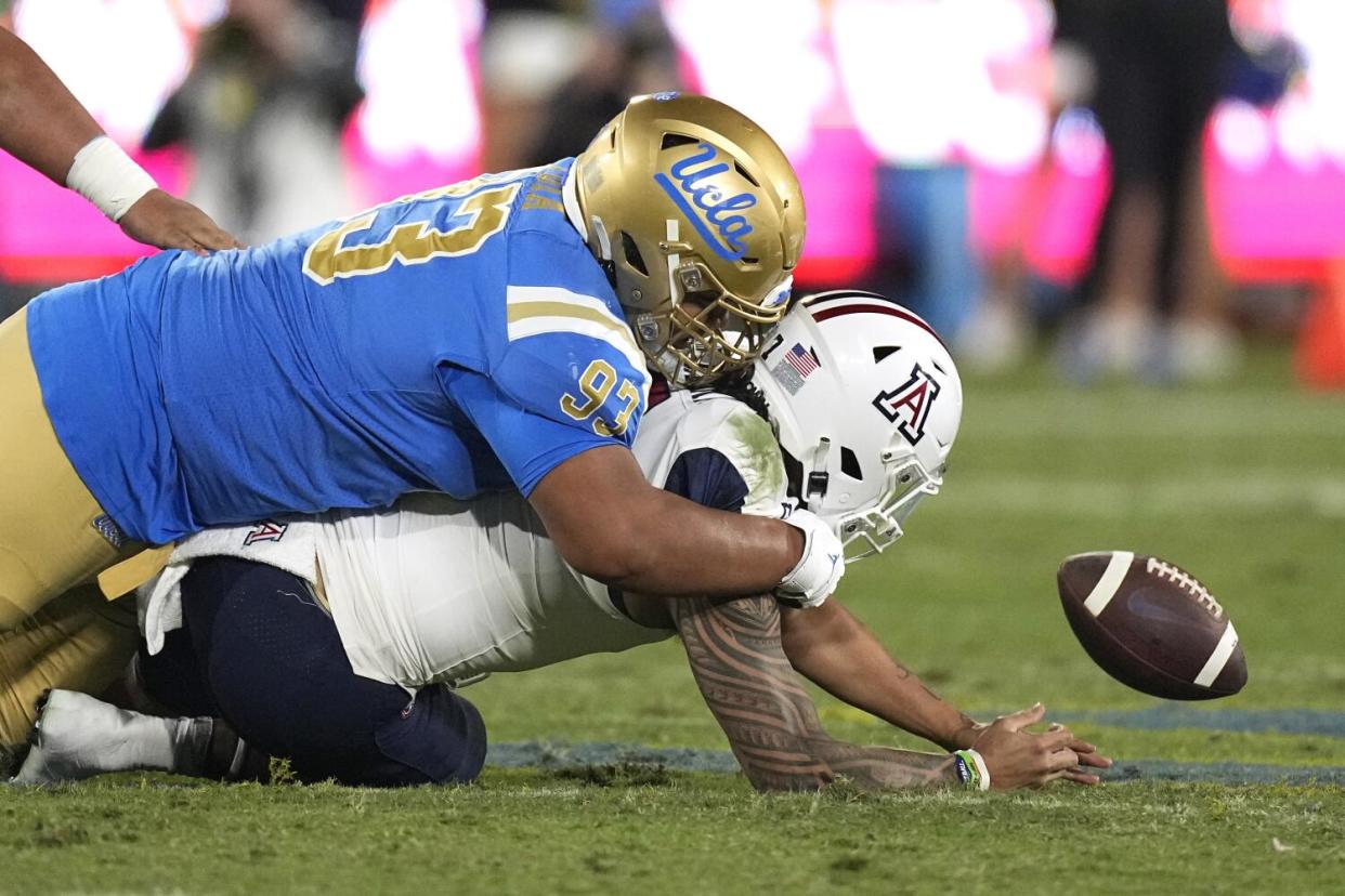 UCLA defensive lineman Jay Toia forces Arizona quarterback Jayden de Laura to fumble as they fall to the ground after a hit.