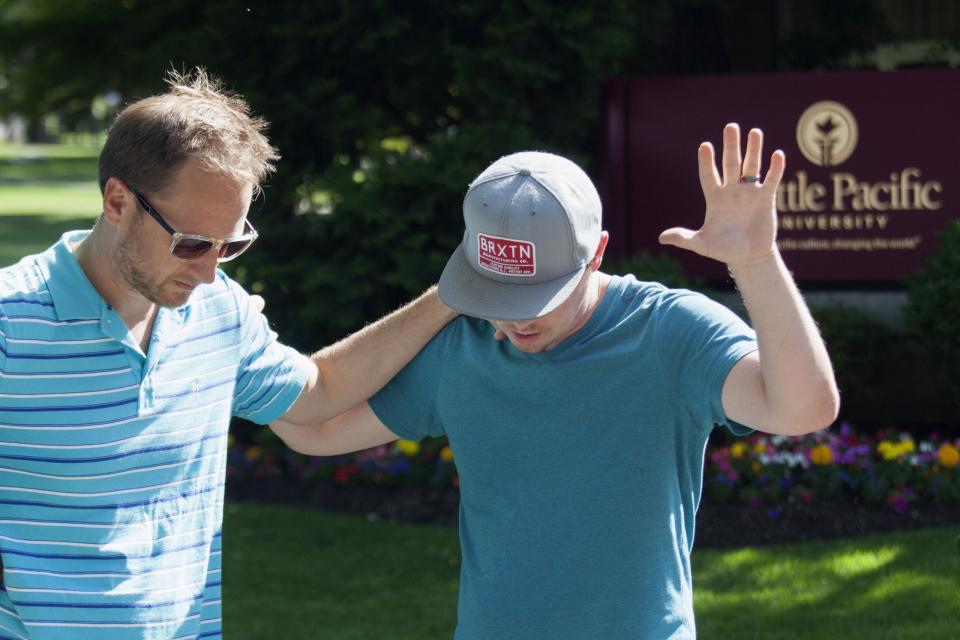 Local pastor Tim Gaydos (L) prays with Chris Holt, a Seattle Pacific University alumnus, at Seattle Pacific University after the campus was evacuated due to a shooting in Seattle, Washington June 5, 2014. (REUTERS/David Ryder)