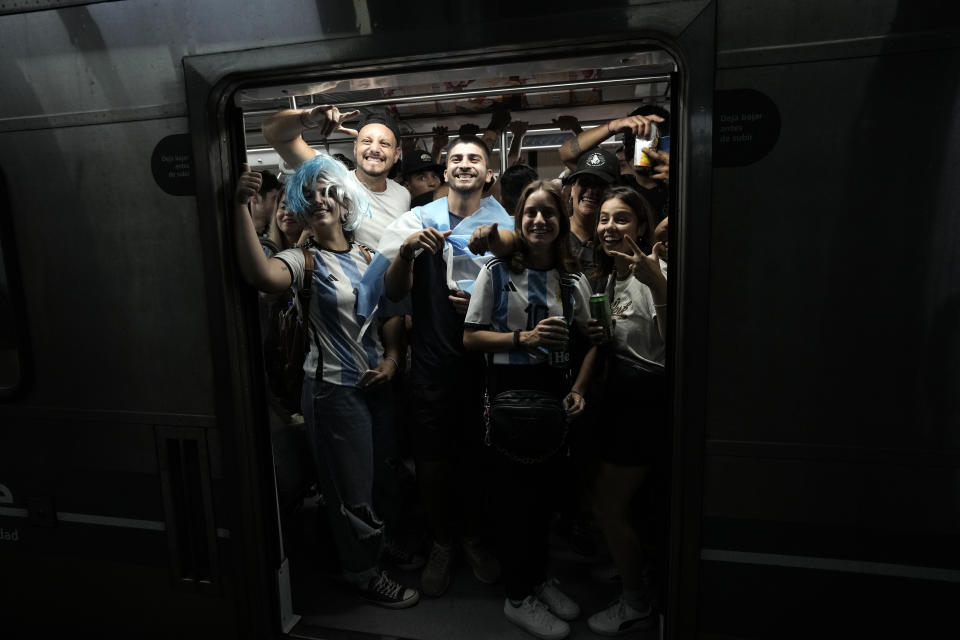 Argentina soccer fans celebrate their team's victory over Croatia after watching the team's World Cup semifinal match in Qatar on TV, as they enter the subway in Buenos Aires, Argentina, Tuesday, Dec. 13, 2022. (AP Photo/Rodrigo Abd)